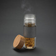 Doppelwandige Glasflasche mit Bambusdeckel und grauem Sleeve warmer Tee