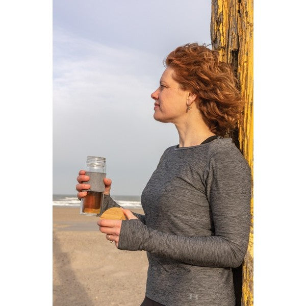 Frau am Strand mit doppelwandiger Glasflasche mit Bambusdeckel
