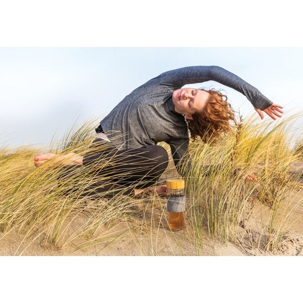 Frau am Strand mit doppelwandiger Glasflasche mit Bambusdeckel